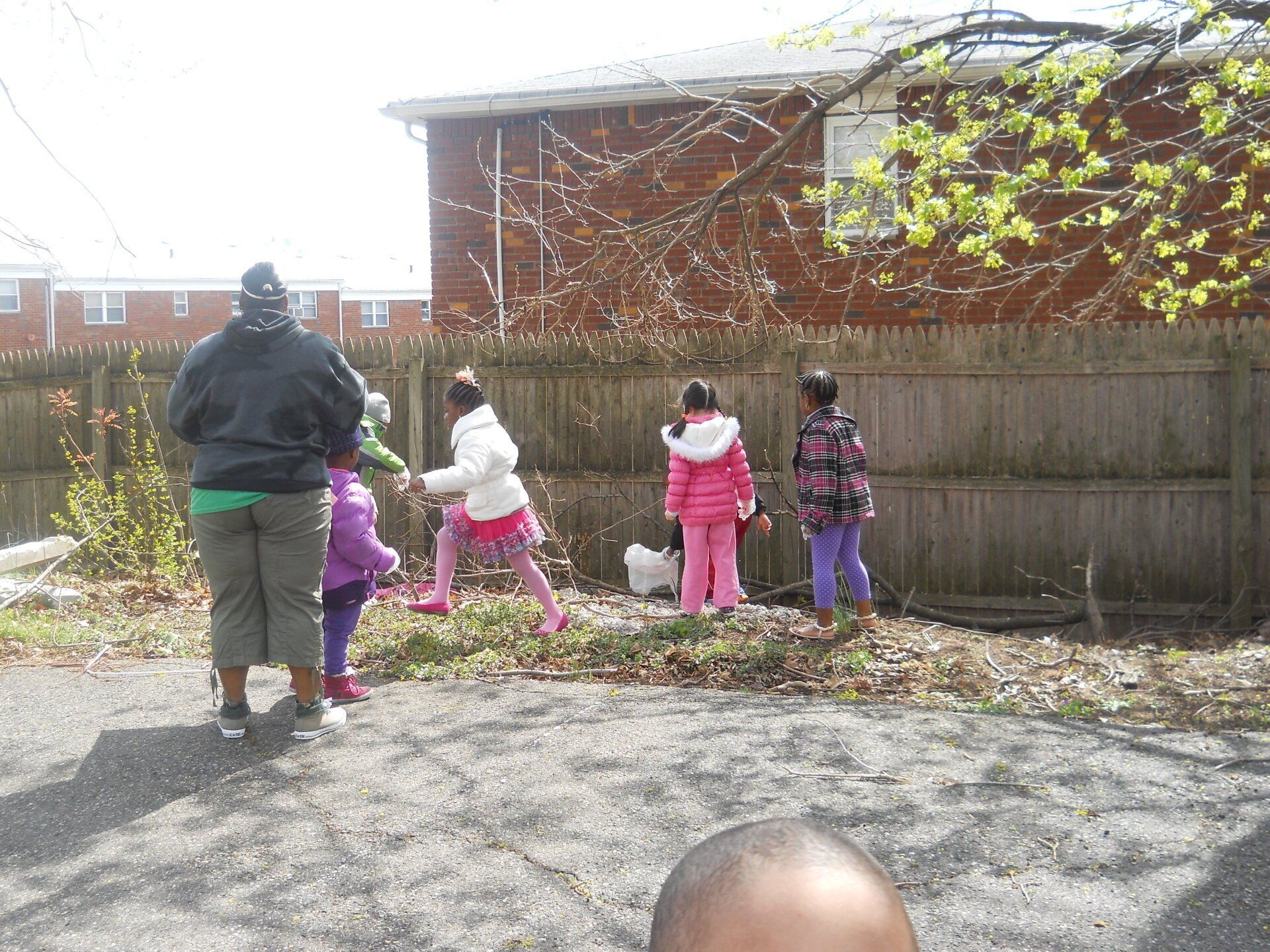 A group of children are standing in front of a wooden fence.