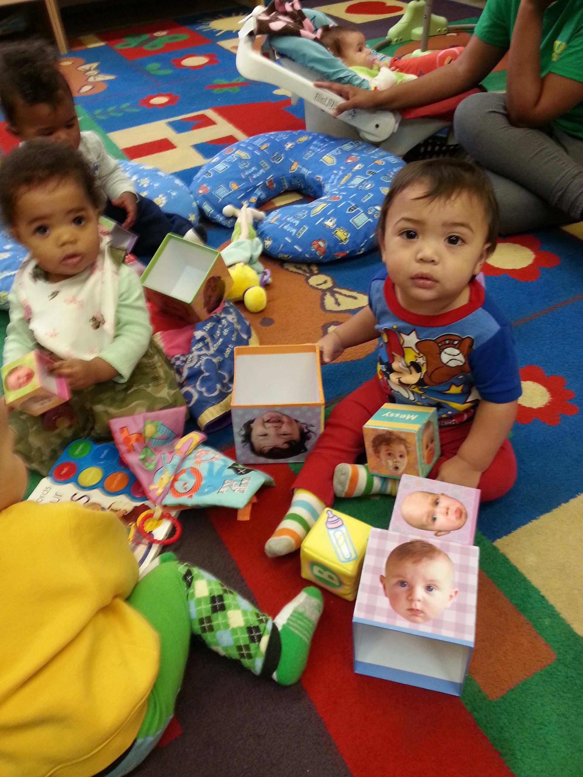 A group of babies are sitting on the floor playing with toys