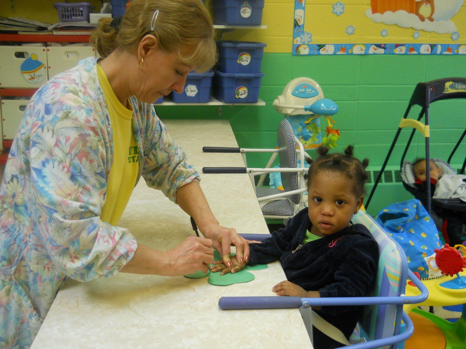A woman is playing with a child in a high chair
