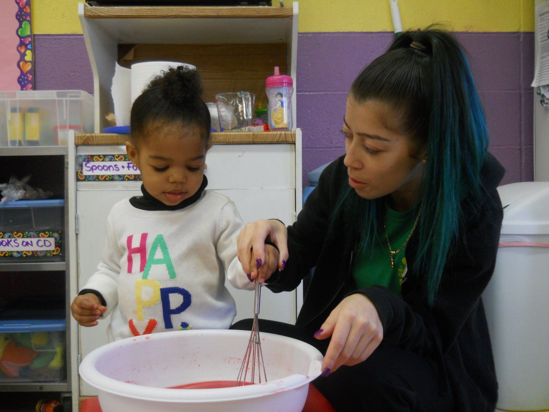 A woman and a little girl are mixing something in a bowl.