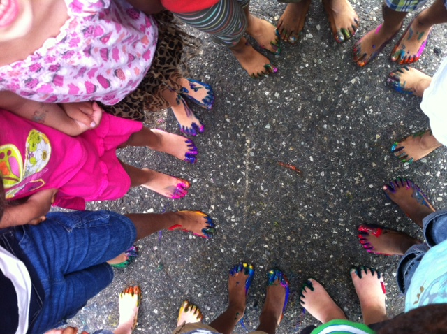 A group of children standing in a circle with their feet painted in different colors