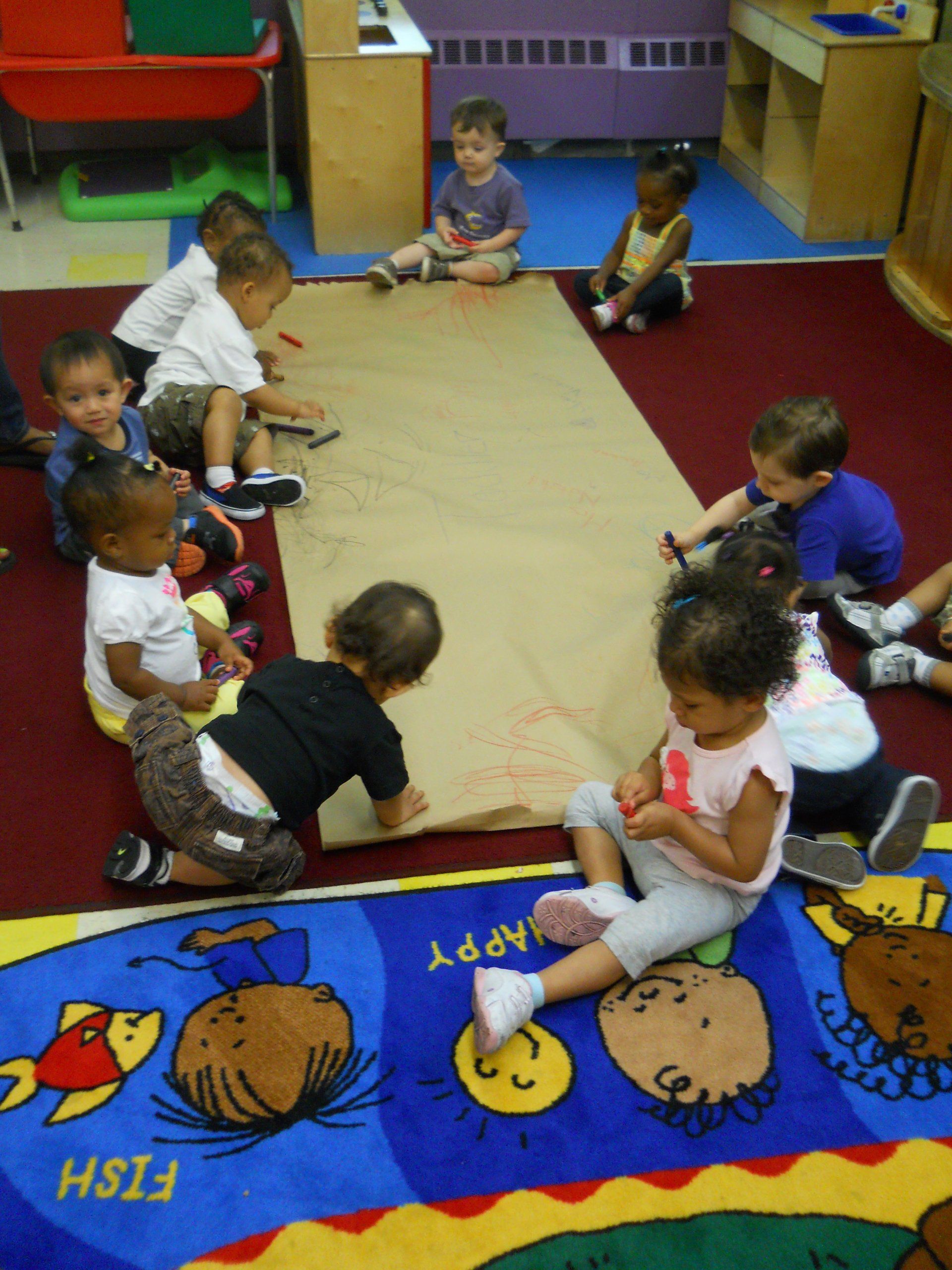 A group of children are sitting on a rug that says fish