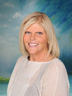 A woman in a white shirt is smiling for the camera.