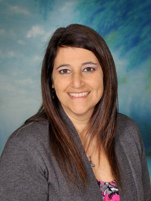 A woman is smiling for a picture in front of a blue background.