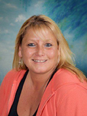 A woman in a pink hoodie is smiling for the camera