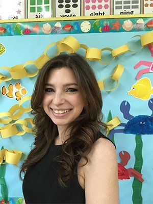 A woman is smiling in front of a bulletin board with numbers on it.