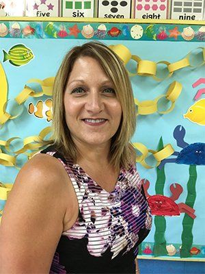 A woman is standing in front of a classroom bulletin board.