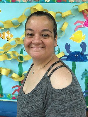 A woman is smiling in front of a bulletin board with fish and crabs on it.