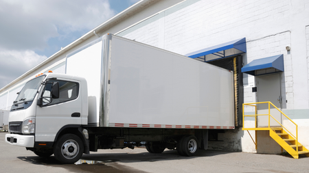 White delivery truck at loading dock of a warehouse; yellow stairs.