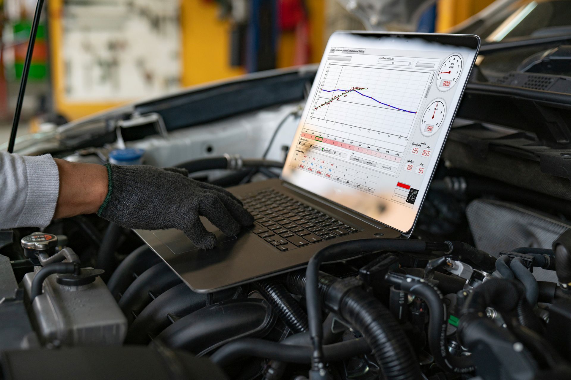 A man is using a laptop computer to check the engine of a car.