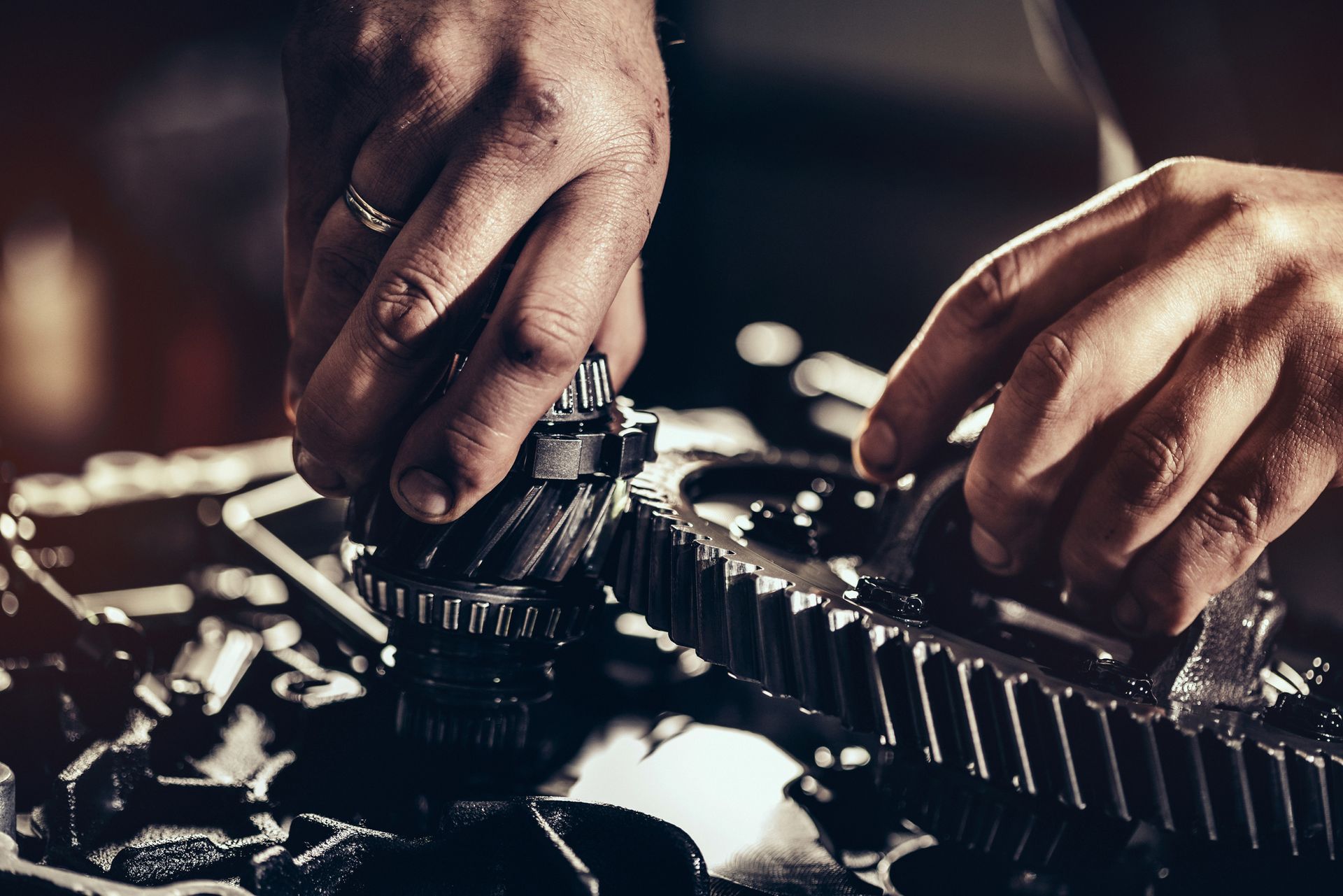 A close up of a person's hands working on a gear.