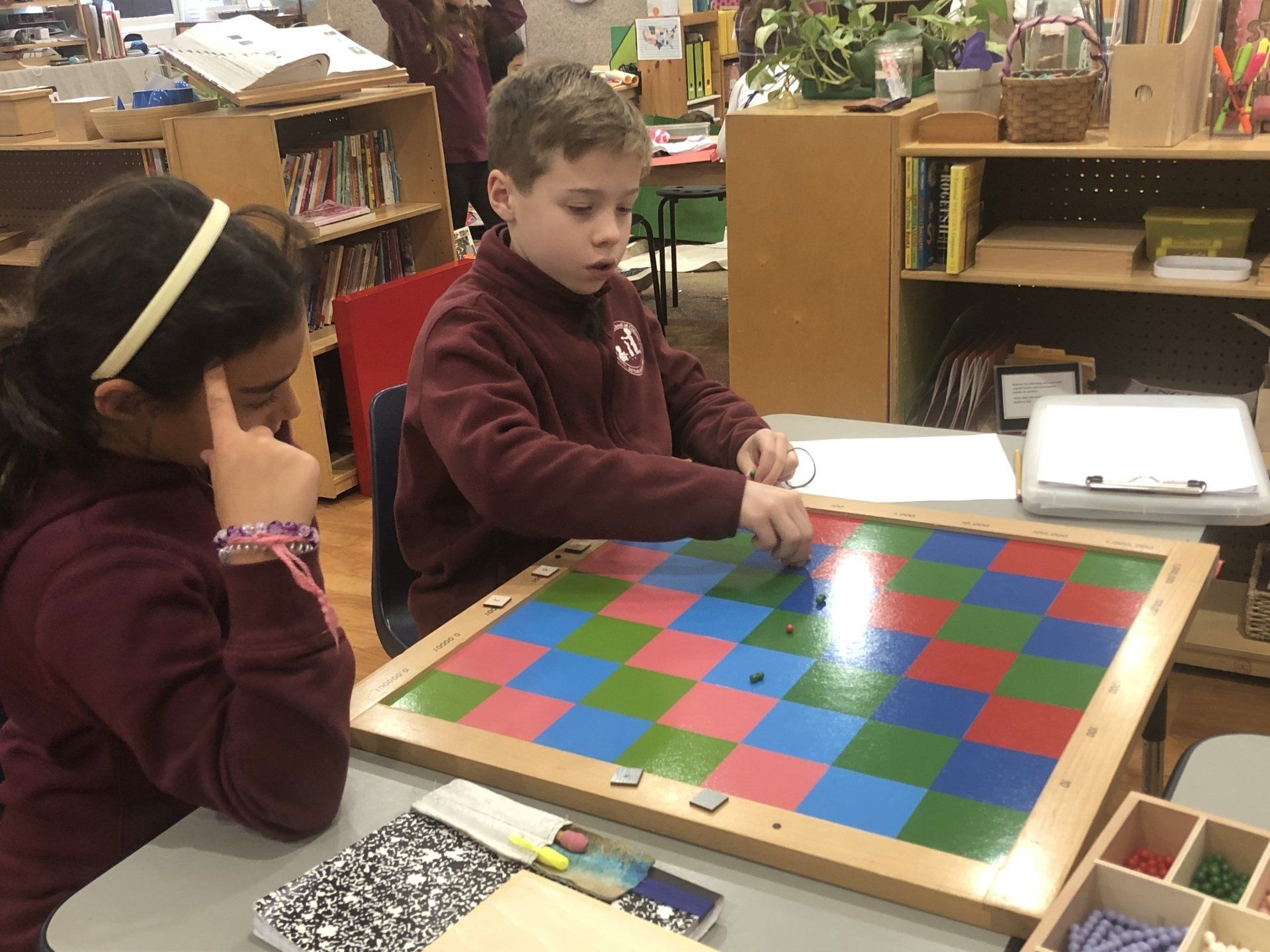 Two Montessori children are working with Montessori material.