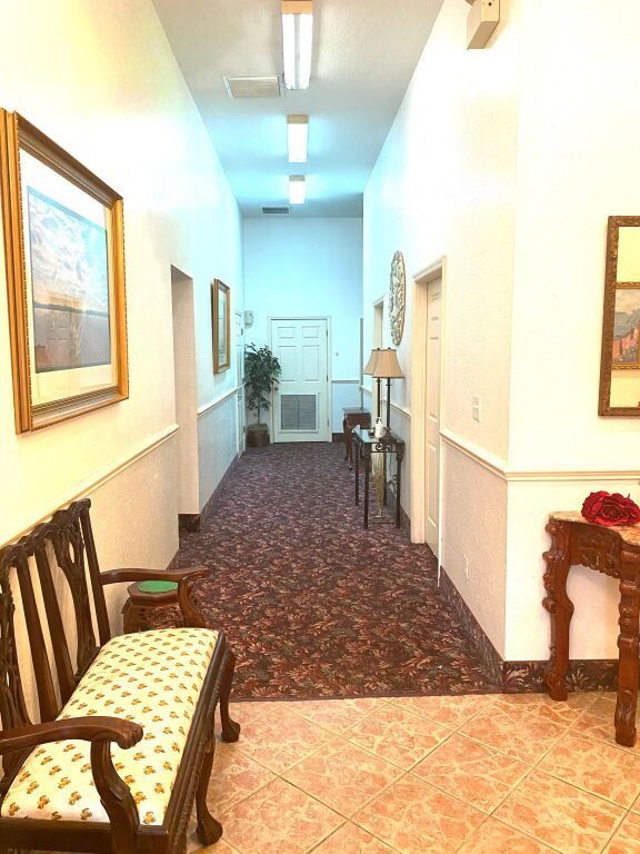 Hallway with patterned carpet, artwork, and decorative furniture.