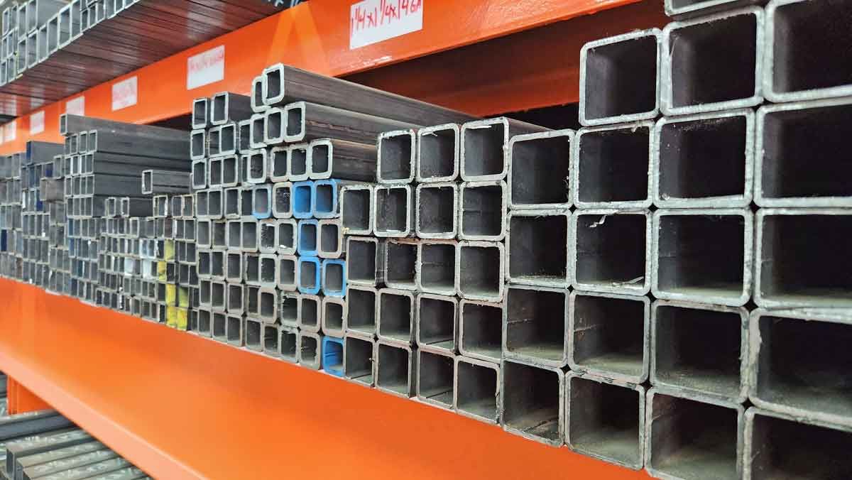 A bunch of square metal pipes are stacked on top of each other on a shelf.