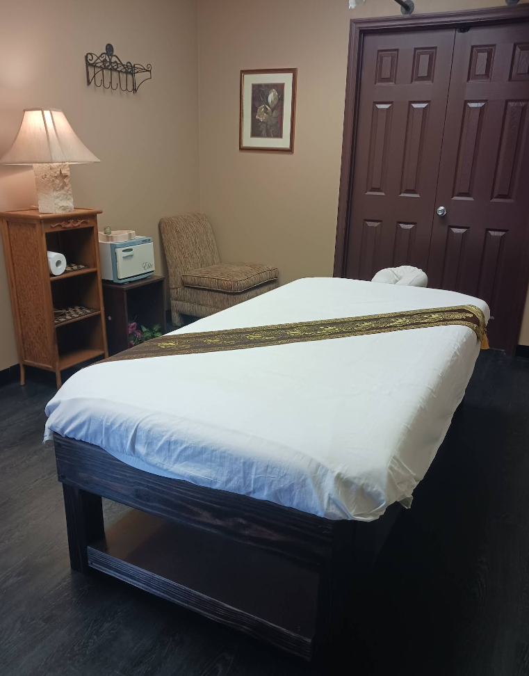 A massage table in a room with a chair and a lamp