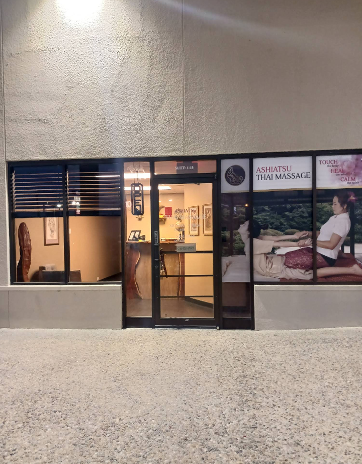 A store front with a woman sitting on a couch in the window
