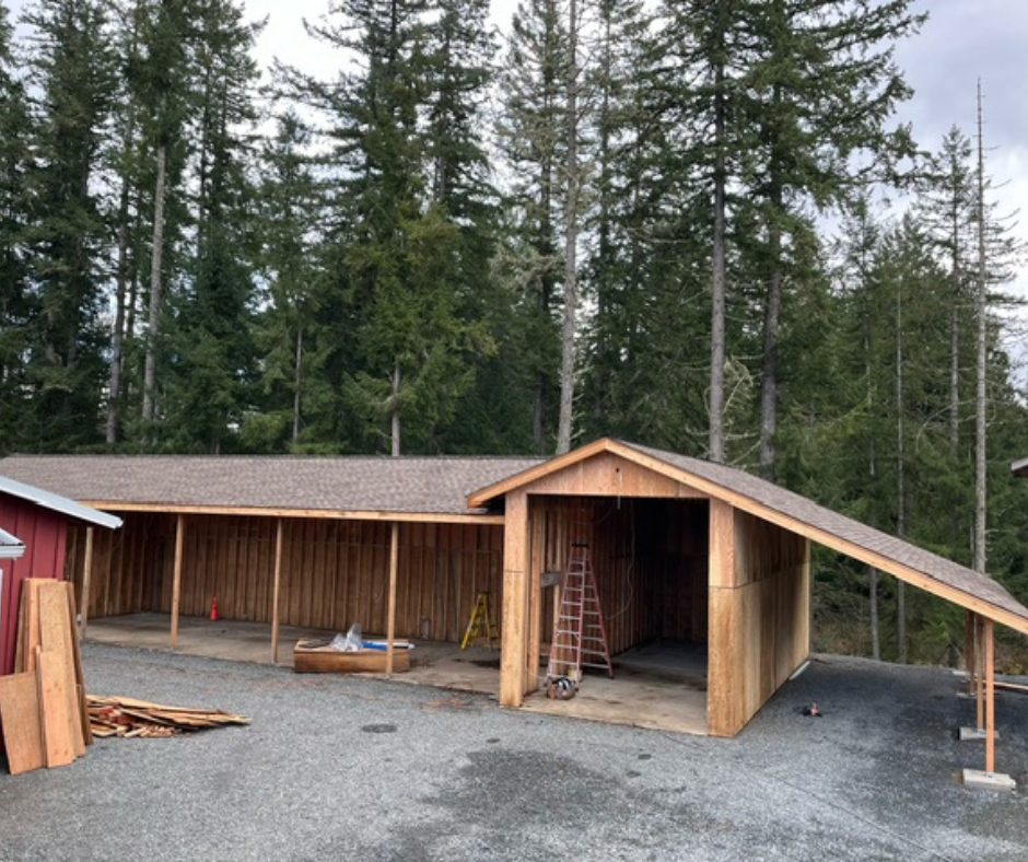 A wooden shed is being built in the middle of a forest