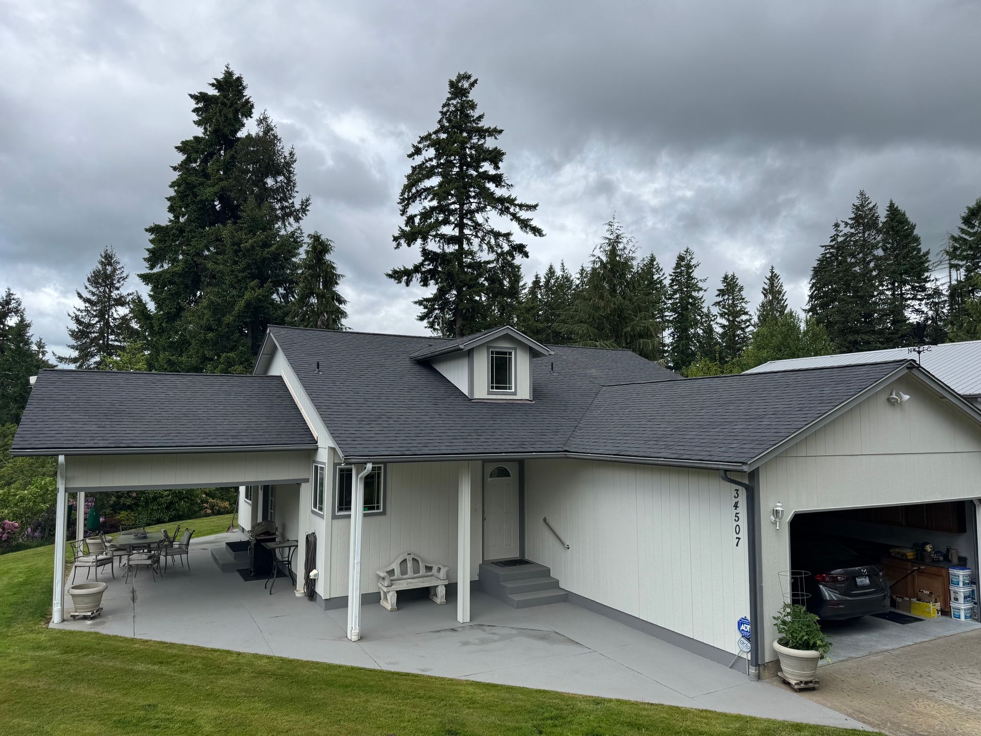 A white house with a black roof and a garage