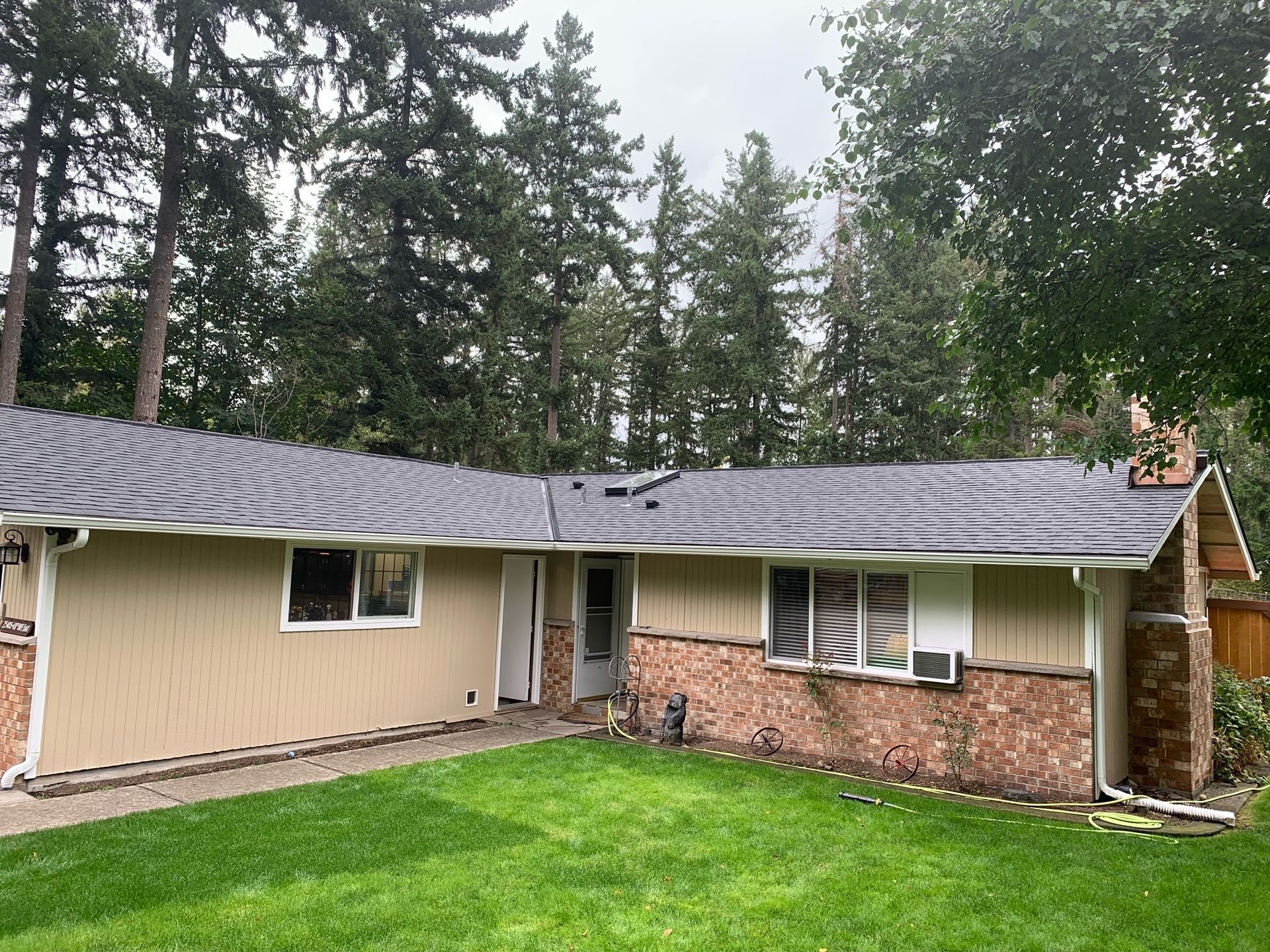 A house with a gray roof and a large lawn in front of it.