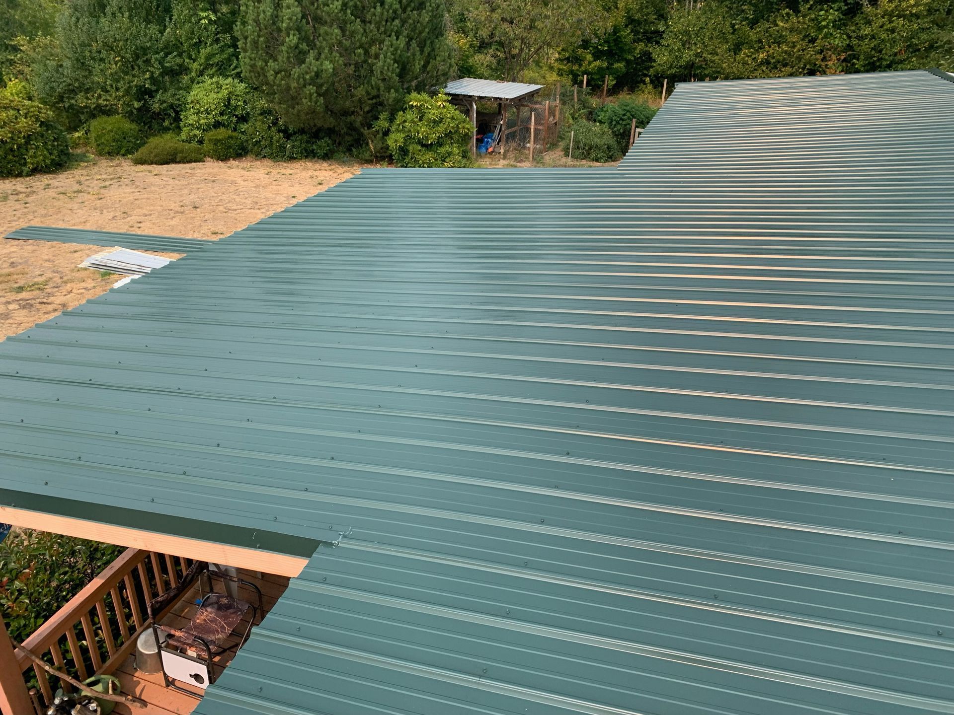 A green metal roof is being installed on a house.