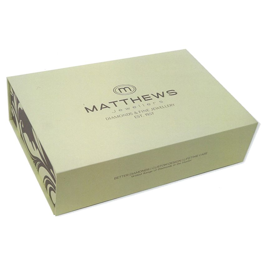 A cream-colored box with the Matthews Jewellers logo in black on the lid, corner with swirling patterns.
