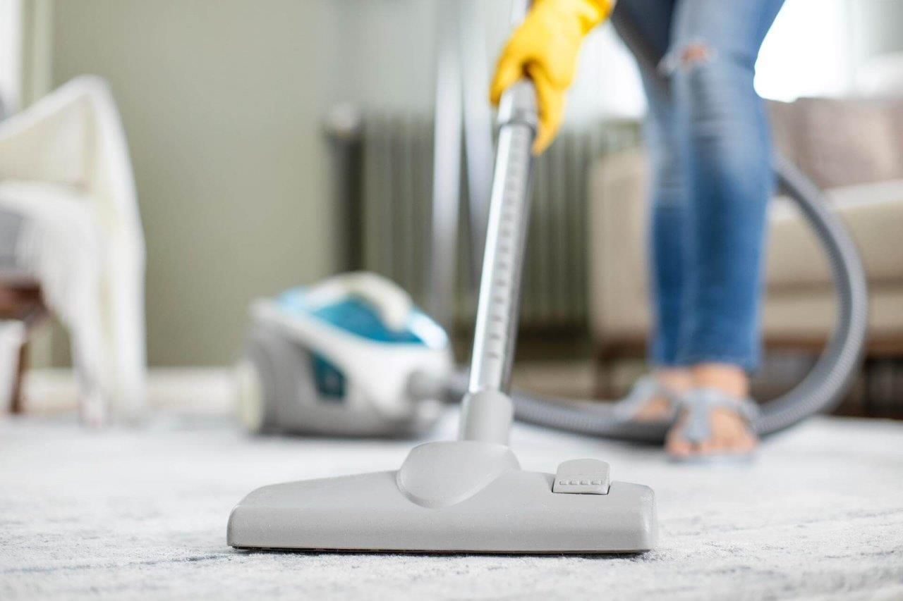 Una donna sta usando un aspirapolvere per pulire il tappeto in un soggiorno.