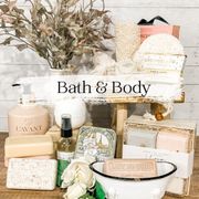 Bath and body products arranged on a wooden stool: soaps, lotions, and loofahs in neutral tones.