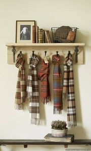 Wooden shelf with plaid scarves hanging from hooks, books, and decor.