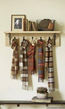 Wooden shelf with plaid scarves hanging from hooks, books, and decor.