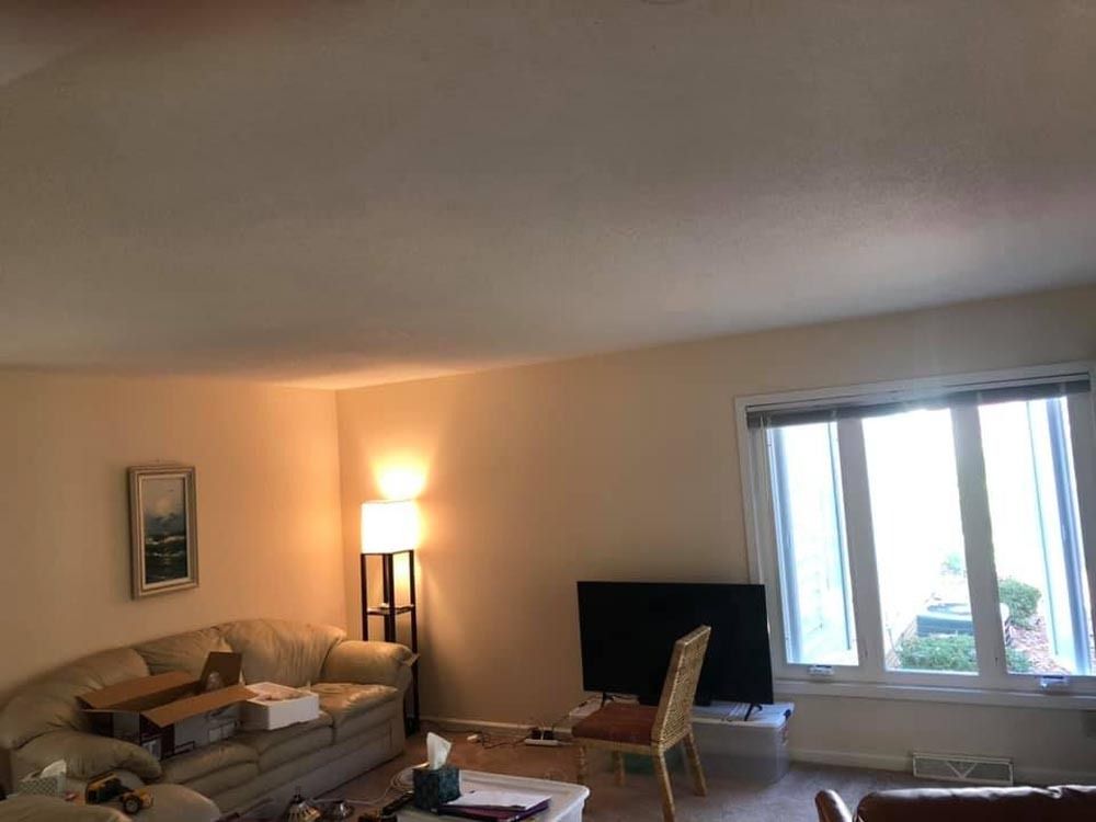 Living room with sofa, TV, floor lamp, and window with curtains.