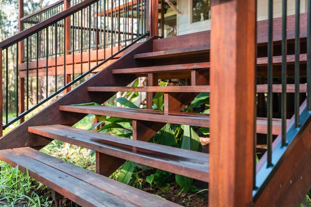 A Set Of Wooden Stairs Leading Up To A House With A Metal Railing — Sedah Home Improvements In Port Macquarie, NSW