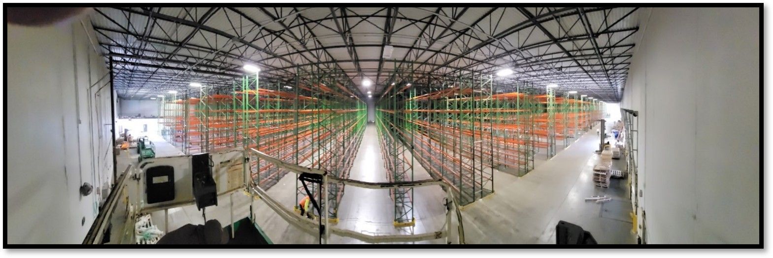 Wide interior view of a warehouse with tall shelving filled with boxes, viewed from a high vantage point.