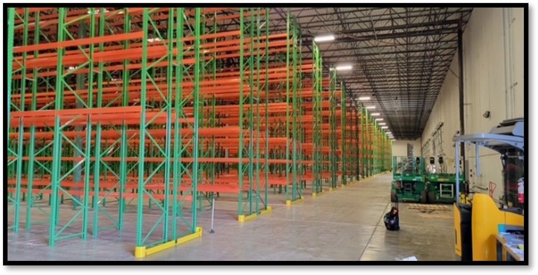 Warehouse interior with tall orange and green industrial shelving units.