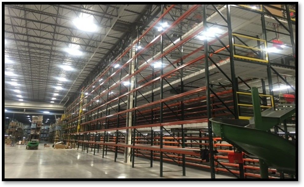 Warehouse interior with multi-level shelving, bright lights, and concrete floor.