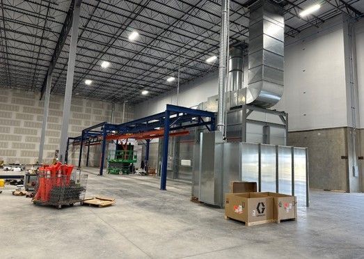 Industrial warehouse with a paint line system; metal structures, ventilation, and boxes.