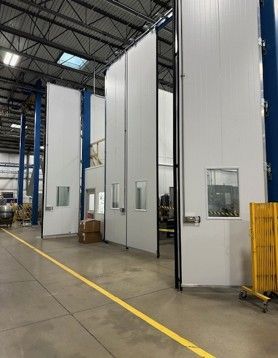 White industrial partitions in a warehouse setting, with windows and open doorways.