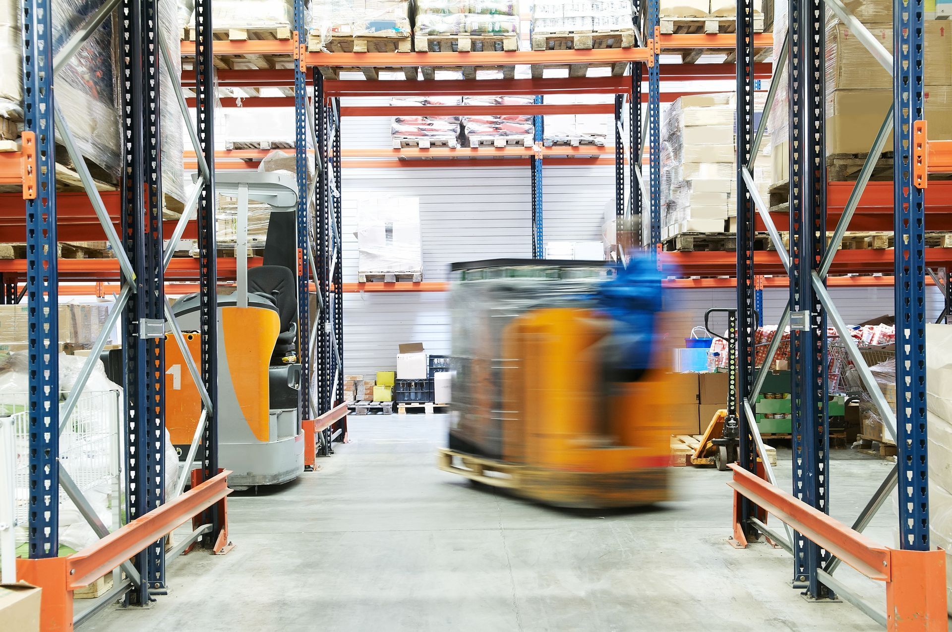 Warehouse interior with a blurred forklift carrying a load down an aisle. Warehouse interior with a blurred forklift carrying a load down an aisle.