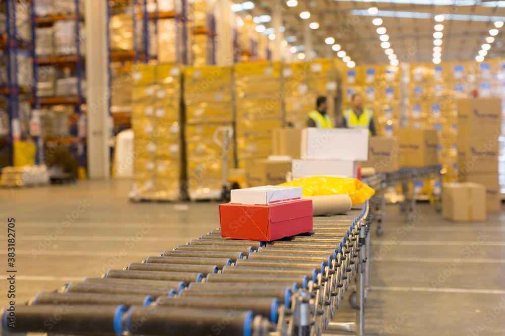 Cardboard boxes moving along a conveyor belt in a white industrial setting.