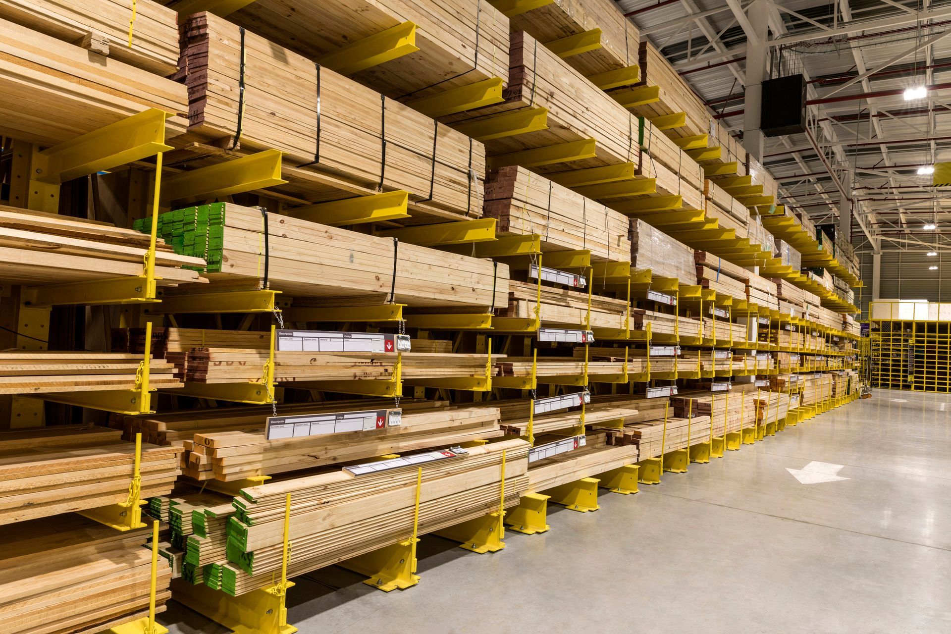 Rows of lumber stored on yellow shelving in a large warehouse. Rows of lumber stored on yellow shelving in a large warehouse.