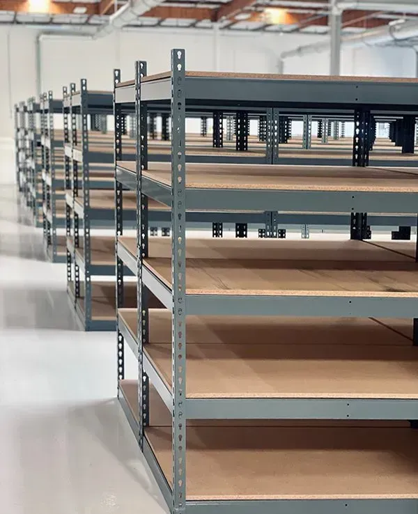 Warehouse interior with tall shelving packed with cardboard boxes and packaged goods.