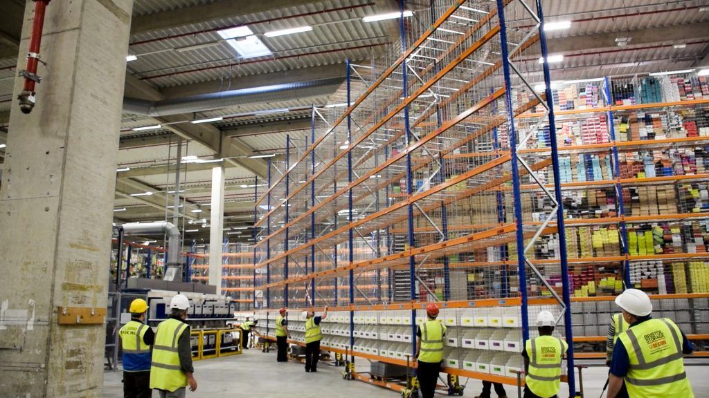 Stack of white boxes in an empty warehouse, against a backdrop of metal beams and concrete flooring.