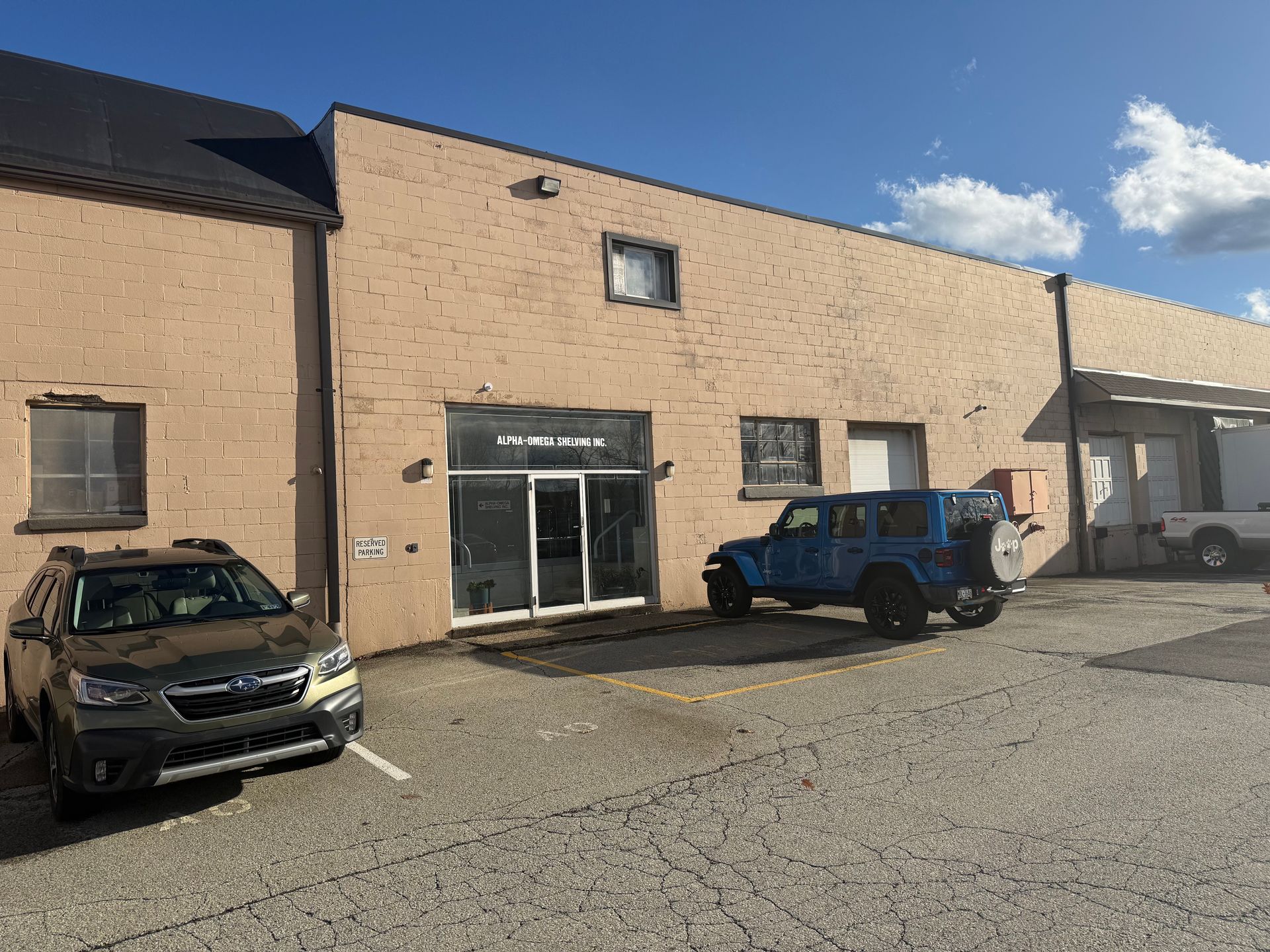 Man in hard hat and vest inspecting shipping container, holding tablet outdoors.