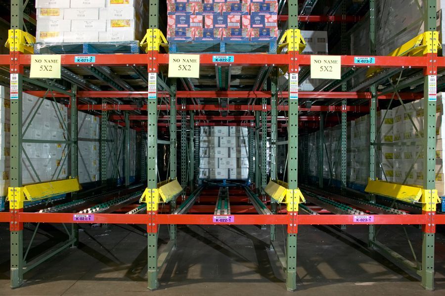Warehouse racking system with palletized goods and flow lanes. Red, green, and yellow metal. Warehouse racking system with palletized goods and flow lanes. Red, green, and yellow metal.