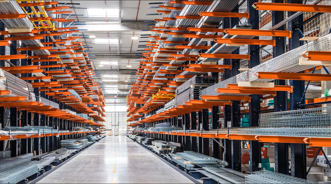 Two workers observing a container lifted by a forklift in a shipping yard, surrounded by blue and orange containers.