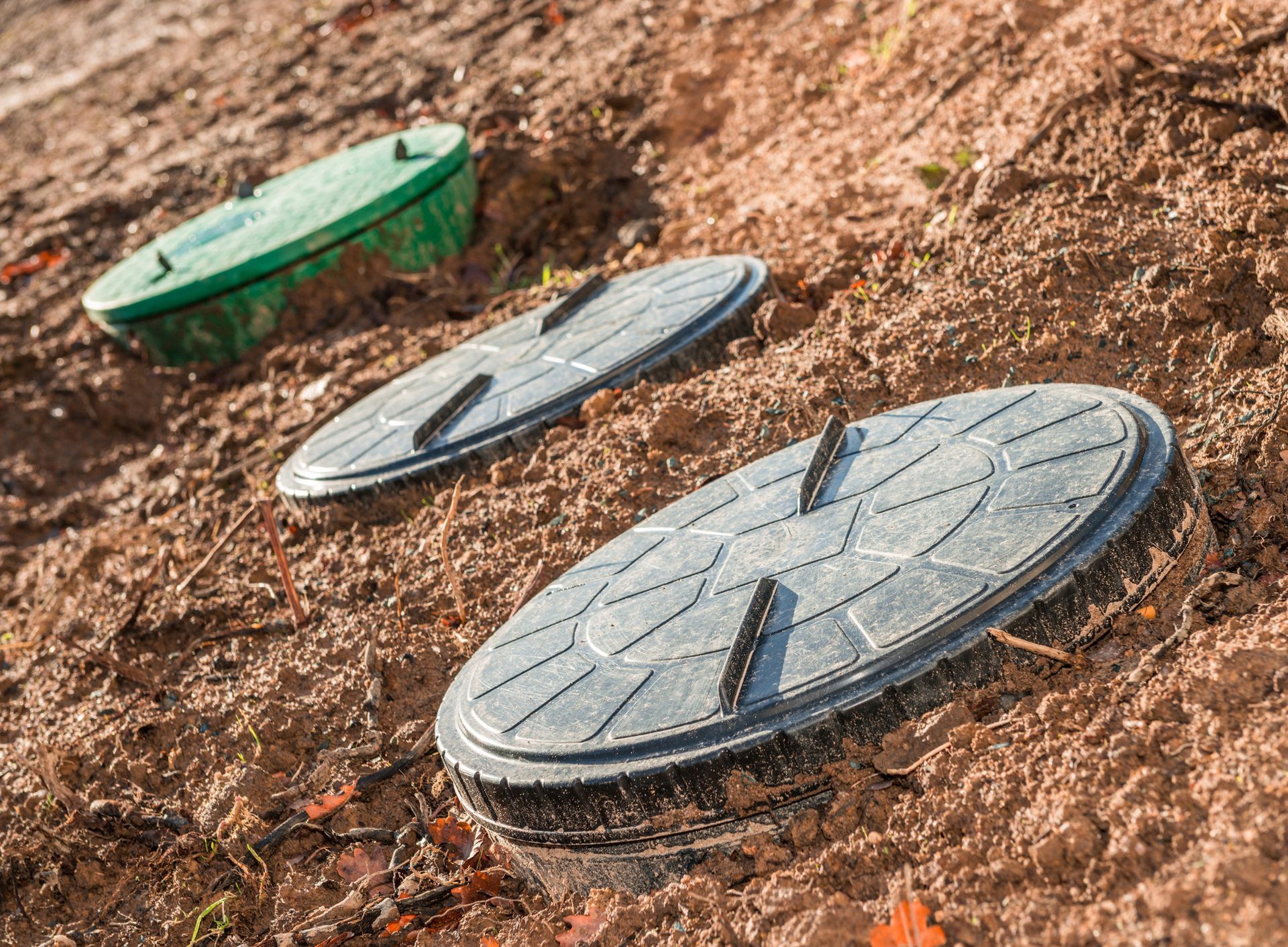 Domestic septic tank openings, jutting from the brown dirt.