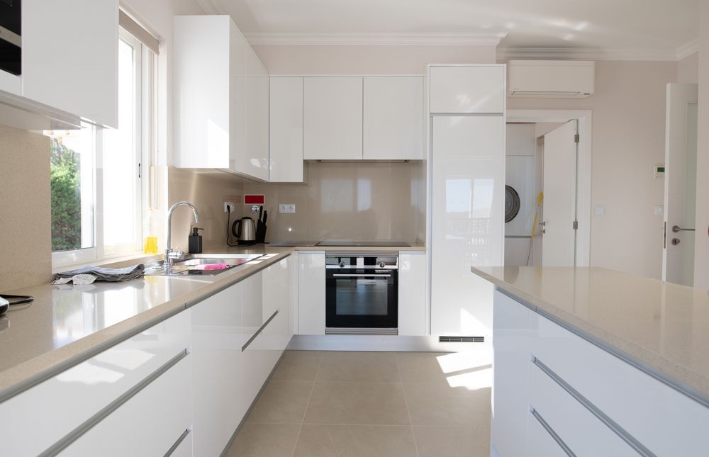 A kitchen with white cabinets, a stove, a sink, and a window — Stone Effects In Forest Glen, QLD