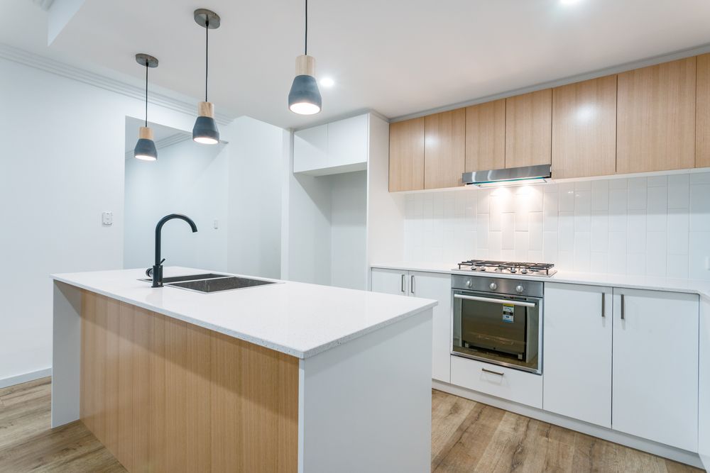 A Kitchen With White Cabinets and Wooden Cabinets and a Large Island in the Middle — Stone Effects In Forest Glen, QLD