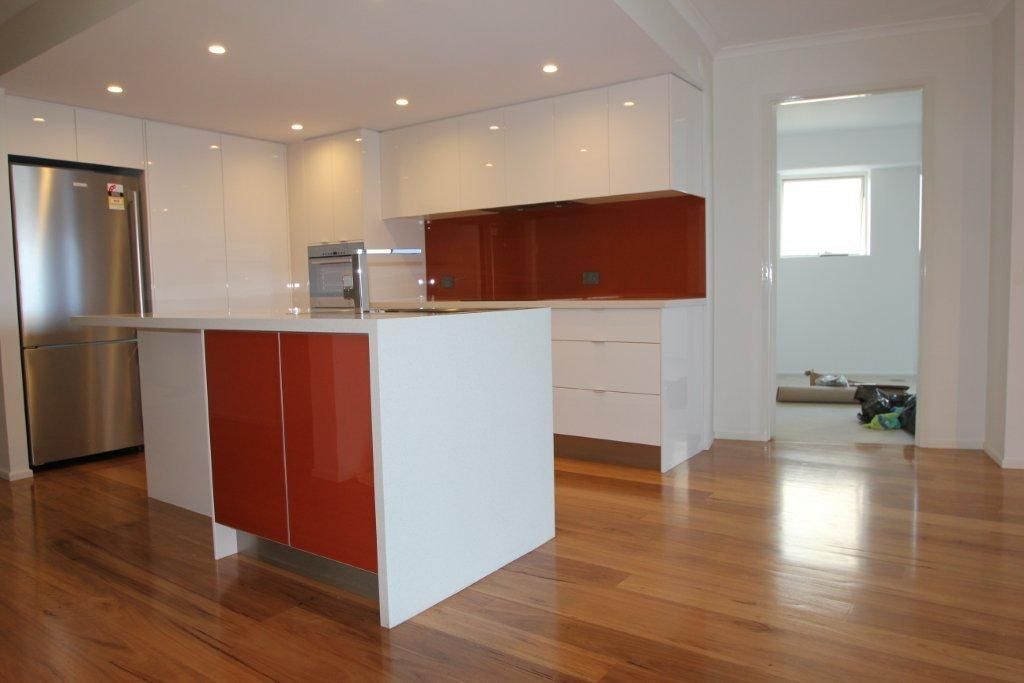 A Kitchen With Red Cabinets and White Counter Tops — Stone Effects In Forest Glen, QLD