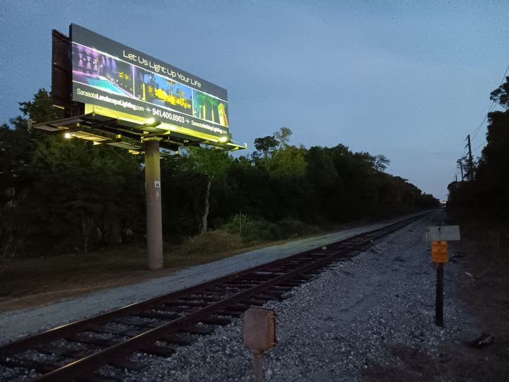 A large billboard on the side of a train track