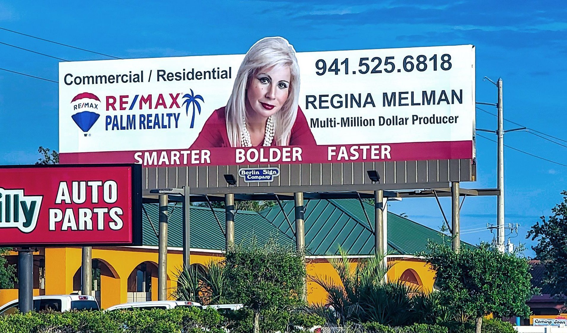 A billboard for regina melman is above an auto parts store